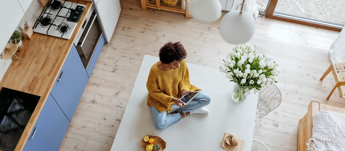 Person sitzt mit Tablet in moderner Küche – Symbol für nachhaltige Energienutzung, digitale Lösungen und Beratung durch GEW Wilhelmshaven.