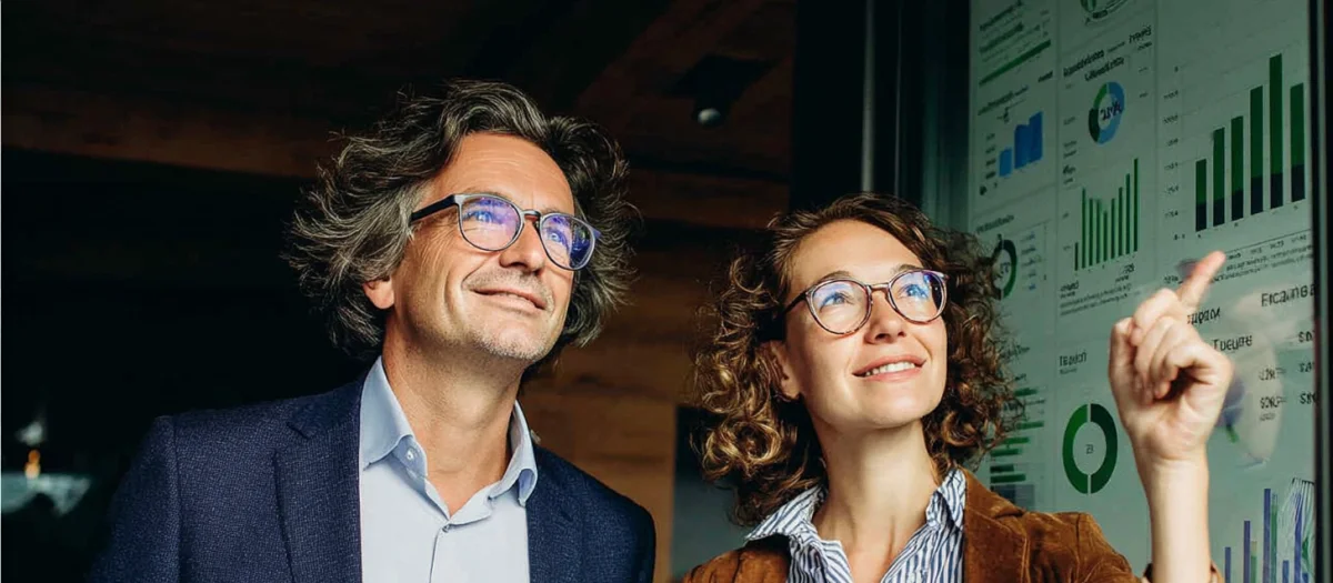 Zwei Personen analysieren Energiedaten auf Bildschirm – Symbol für digitales Energiedatenmanagement und effiziente Energieoptimierung durch GEW Wilhelmshaven.