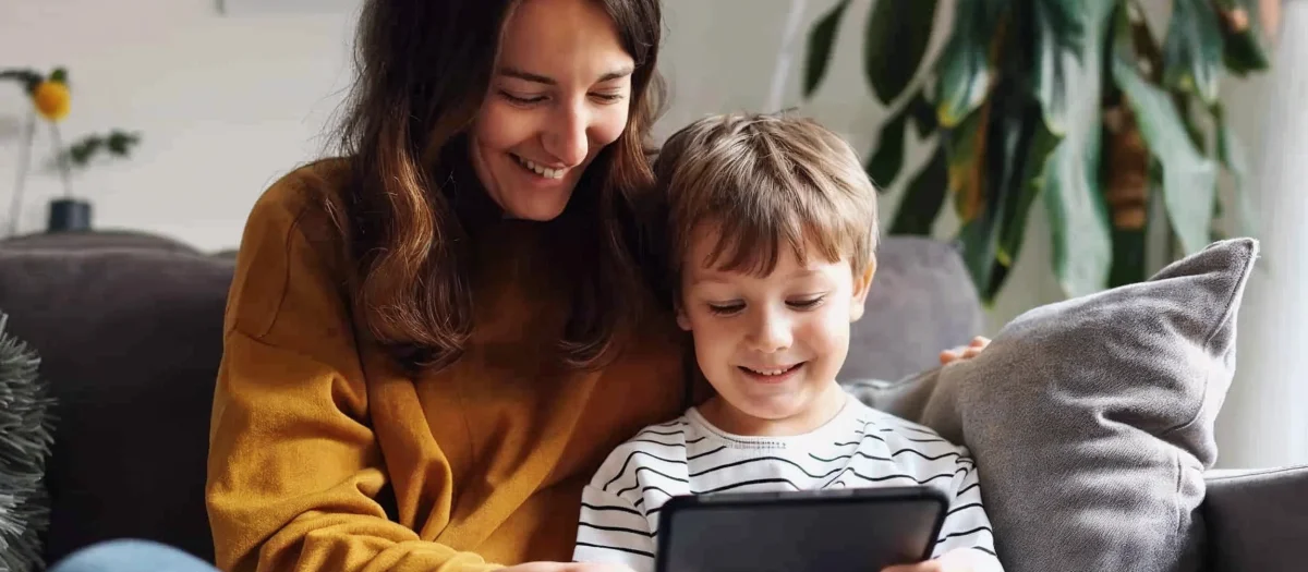 Mutter und Kind sitzen gemütlich auf dem Sofa und schauen gemeinsam auf ein Tablet – Symbol für familienfreundlichen, zuverlässigen Strom von GEW Wilhelmshaven.