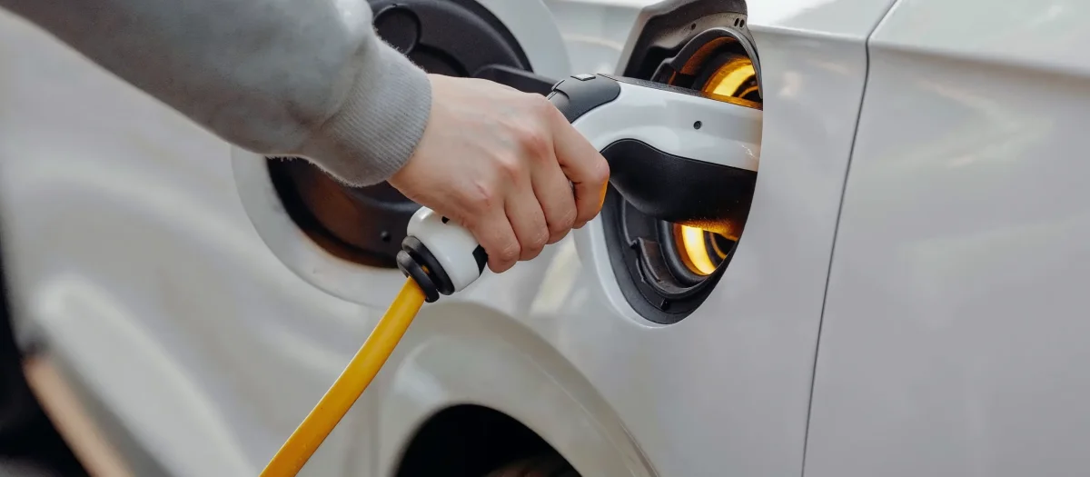 Person lädt Elektroauto mit gelbem Ladekabel – Symbol für klimafreundliche E-Mobilität und nachhaltigen havenstrom mobil von GEW Wilhelmshaven.