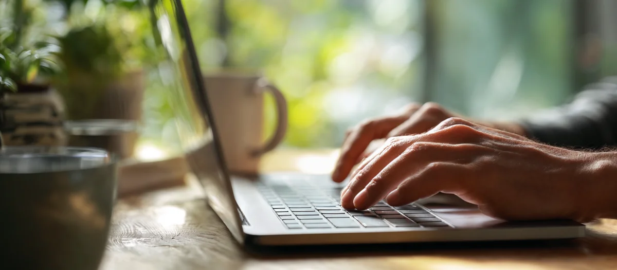 Hände tippen auf Laptop im Sonnenlicht – Symbol für digitalen Kundenservice und transparente Online-Informationen bei GEW Wilhelmshaven.