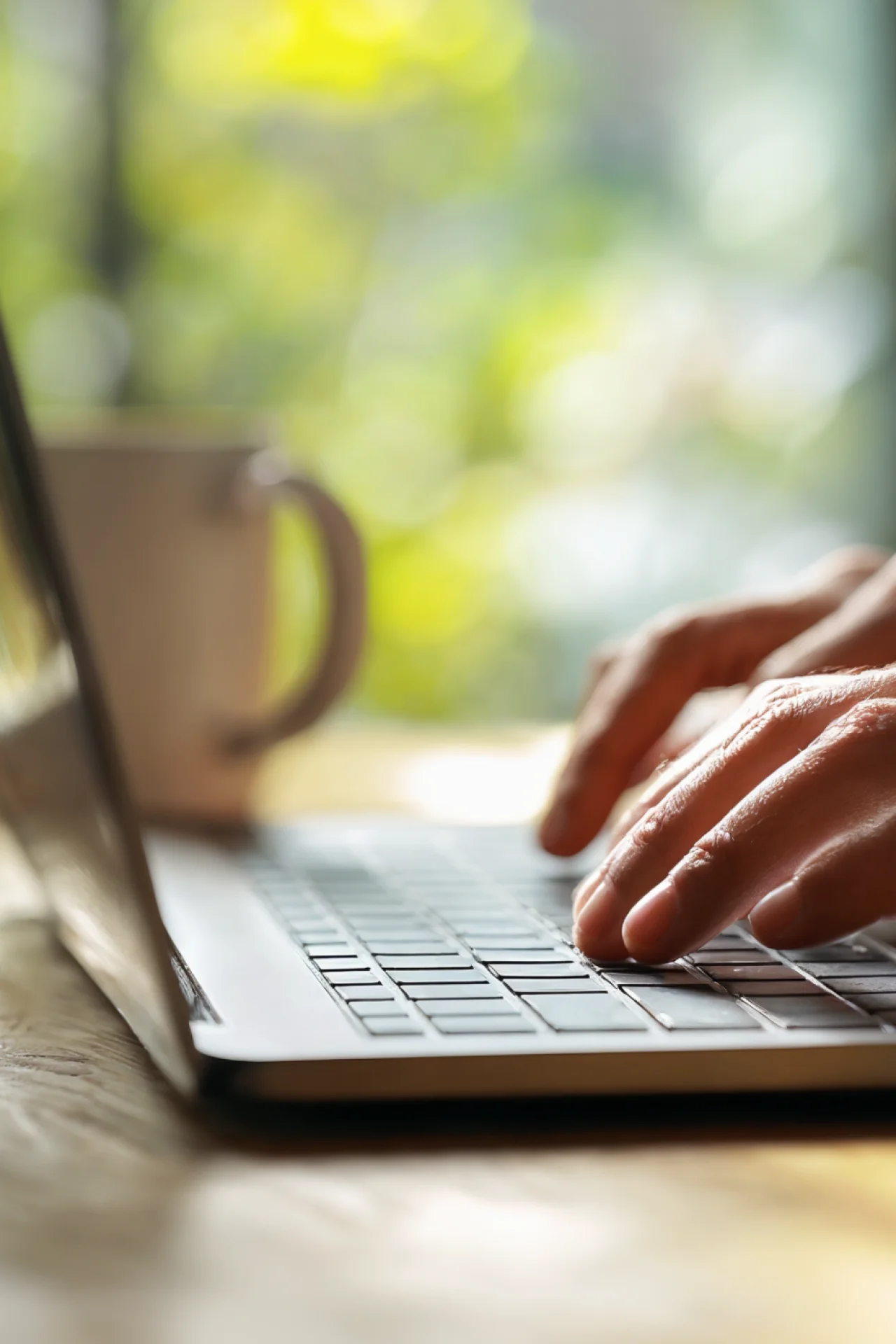 Hände tippen auf Laptop im Sonnenlicht – Symbol für digitalen Kundenservice und transparente Online-Informationen bei GEW Wilhelmshaven.