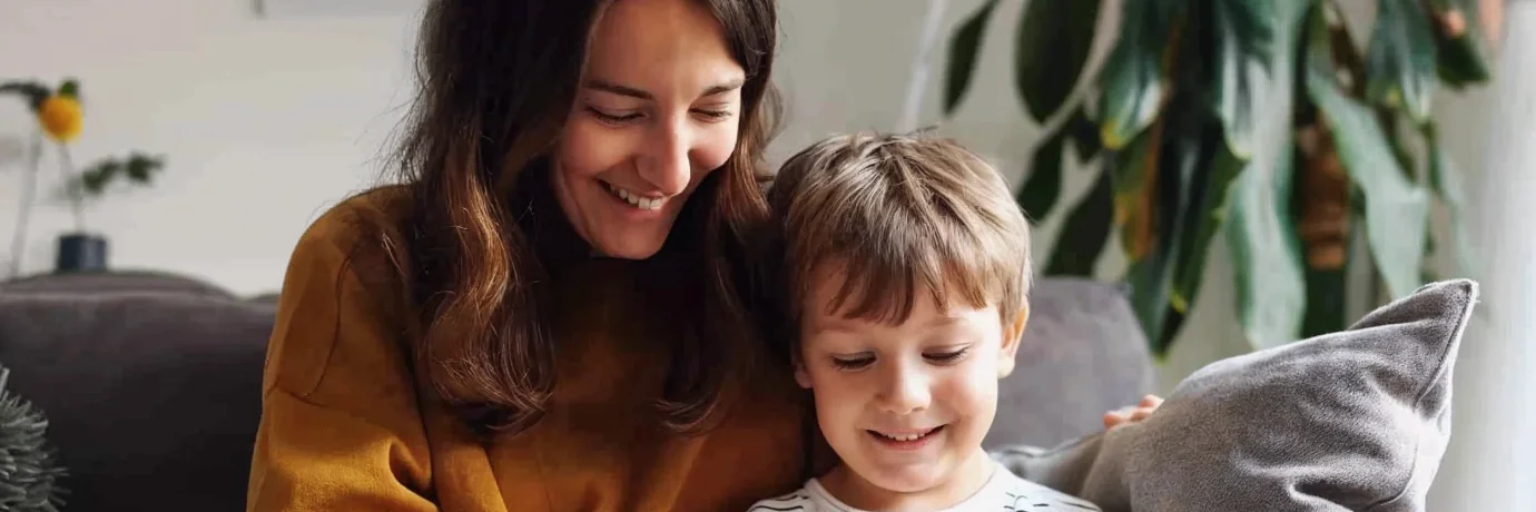 Mutter und Kind sitzen gemütlich auf dem Sofa und schauen gemeinsam auf ein Tablet – Symbol für familienfreundlichen, zuverlässigen Strom von GEW Wilhelmshaven.