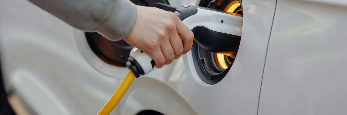 Person lädt Elektroauto mit gelbem Ladekabel – Symbol für klimafreundliche E-Mobilität und nachhaltigen havenstrom mobil von GEW Wilhelmshaven.