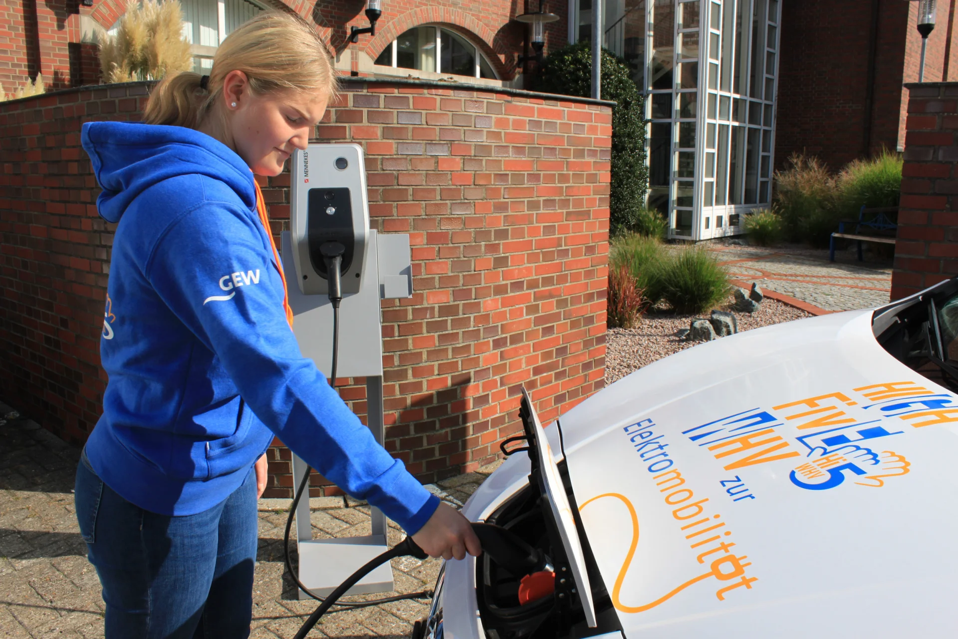 GEW-Mitarbeiterin lädt Elektroauto an moderner Wallbox – Symbol für nachhaltige Elektromobilität und klimafreundlichen Strom von GEW Wilhelmshaven.