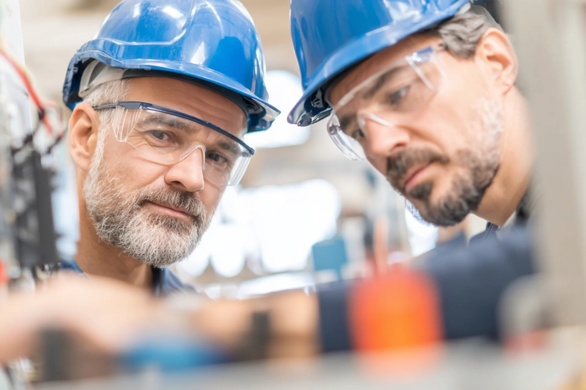 Zwei Techniker mit Schutzhelmen arbeiten konzentriert an einer Anlage – Symbol für Teamarbeit, Fachkompetenz und Karrierechancen in der Energiebranche bei GEW Wilhelmshaven.